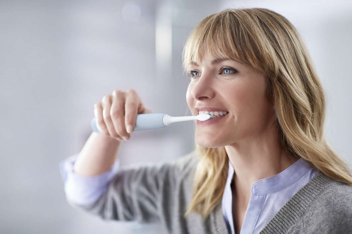 Žena si čistí zuby elektrickou zubnou kefkou